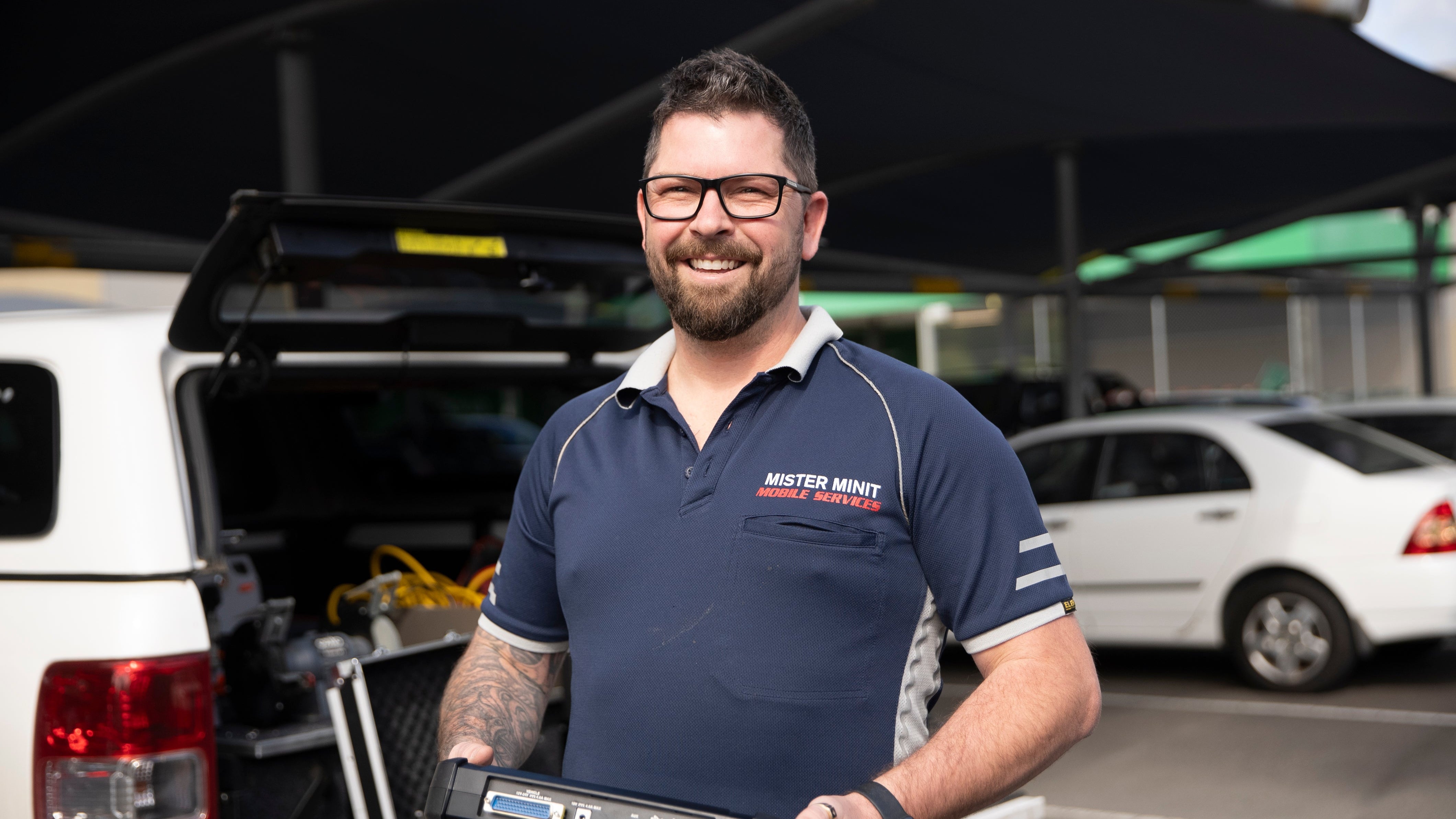 Man holding a diagnostic tool in a car service setting